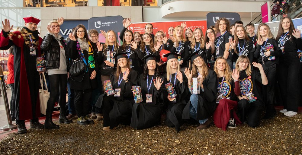 Grupa osób - studenci i Władze UŁ stojący na wielkim sercu ze złotych monet